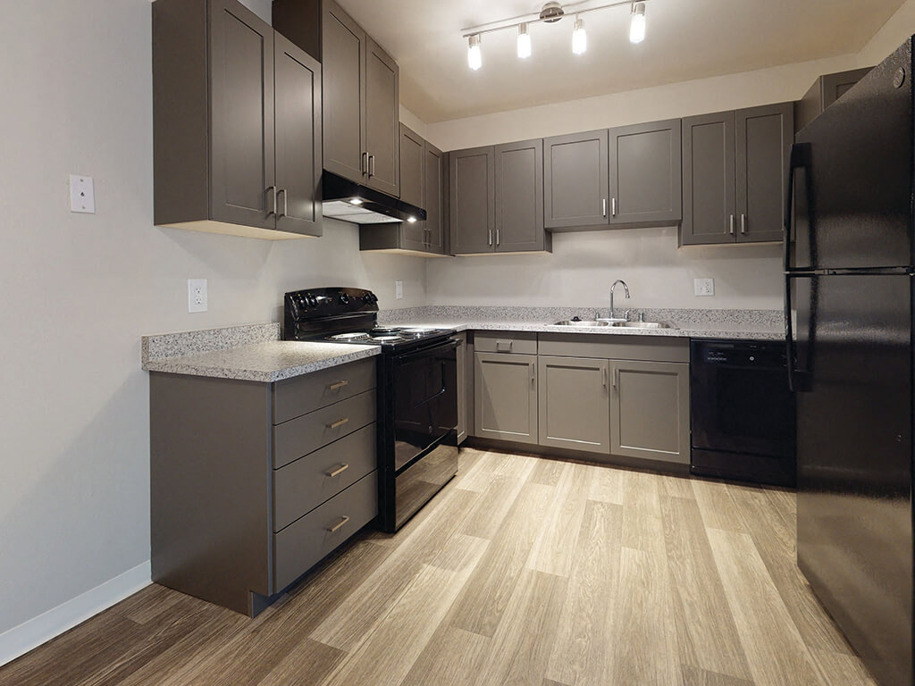 A modern kitchen with dark cabinets and hardwood floors at the Park Villas Apartments in National City, California.